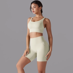 Dettaglio del reggiseno sportivo incrociato e pantaloncini yoga a vita alta in giallo chiaro