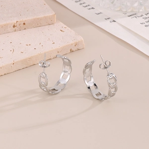 Détail macro de boucles d'oreilles chaînes géométriques argentées aux maillons ajourés