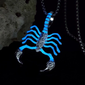 Close-up of retro scorpion pendant glowing blue in the dark with metal chain