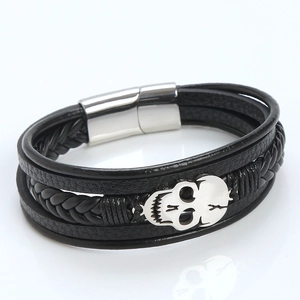 Macro shot of skull charm detail on black braided leather bracelet with magnetic clasp