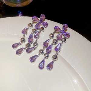 Detailed macro view of vintage purple zircon teardrop tassel earrings on white ceramic