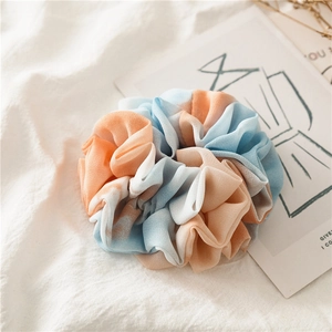 Detailed close-up of blue and orange tie-dye chiffon scrunchie with soft fabric pleats