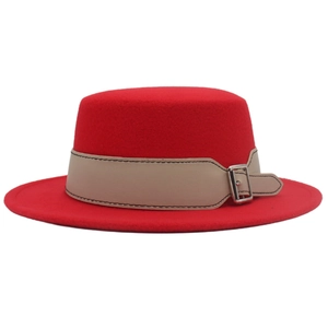 Dettaglio di un cappello di lana rosso con cinturino in pelle marrone chiaro e fibbia in metallo