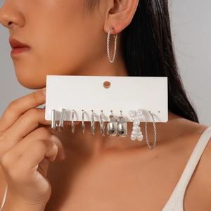 Twelve-piece silver geometric twist hoop earring set with pearl accents on a white card
