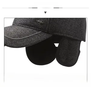 Detail of dark grey tweed winter hat featuring integrated earflaps and sport metal tag