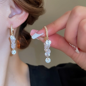Gros plan de boucles d'oreilles pendantes dorées à plusieurs niveaux avec zircons