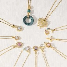 Macro shot of gold necklaces featuring emerald rings, zircon butterflies, and star pendants