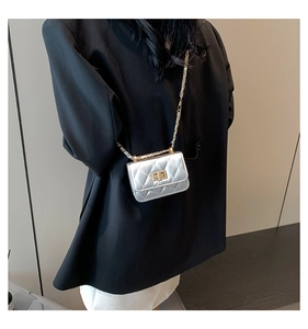 Close-up of silver quilted mini bag with metallic texture and chain strap on a blazer