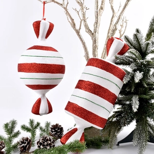 Glittery red and white Christmas candy ornaments hanging with pine cones and golden branches