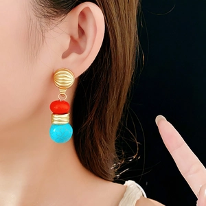 Detail of vintage earrings with gold texture, red oval beads, and turquoise round stones