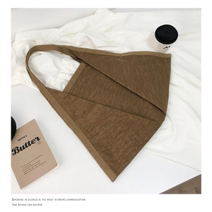 Detail shot of brown pleated tote bag on white fabric with coffee and magazine setup