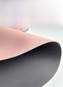 Detail of double-sided faux leather placemat showing pink and grey litchi grain texture