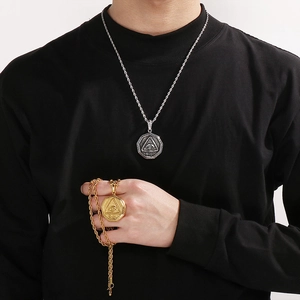 Close-up of silver and gold All-Seeing Eye pendants with twist chains on a male model