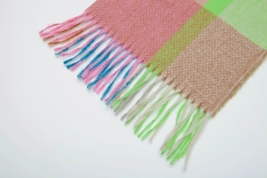 Close-up of thick colorful plaid scarf featuring soft knit texture and rainbow fringe details
