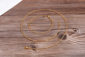 Detail of minimalist 18k gold plated titanium steel thin chain necklace on wooden surface