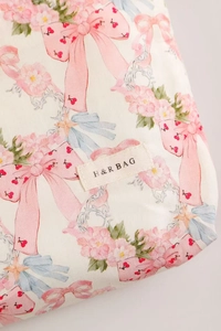 Detailed close-up of pink bow and floral prints on cotton cosmetic bag with H&R logo