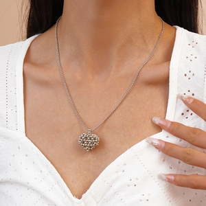 Détail du collier avec pendentif cœur évidé en argent porté sur un haut en dentelle