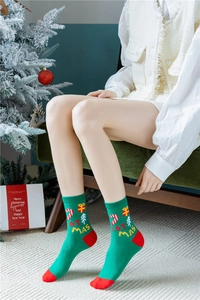 Détail de chaussettes de Noël vertes avec broderie et mise en scène de cadeau festif