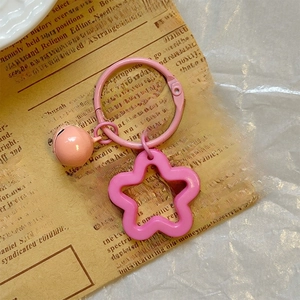 Close-up of pink flower keychain with small bell on vintage newspaper background
