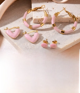 Macro detail of gold-plated titanium steel earrings with pink enamel heart and studs
