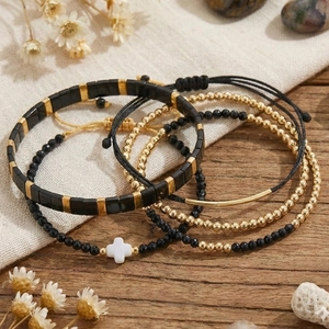 Böhmisches Armbandset in Schwarz und Gold mit Kleeblatt-Anhänger auf Holzuntergrund