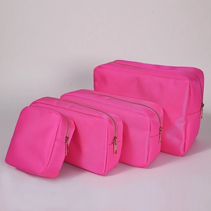 Detailed set of four bright pink nylon cosmetic bags with gold zippers on white back