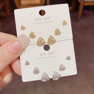 Detailed view of silver and gold triangular stud earring set with pave zircon stones