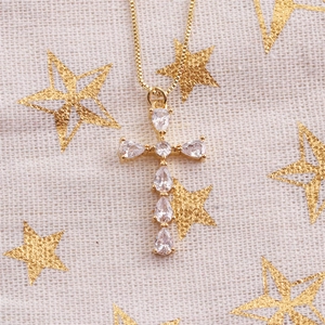Gold 18K plated cross necklace with clear zircons on a beige star pattern fabric