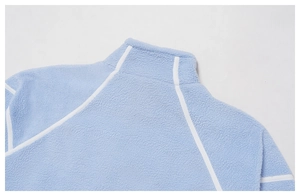 Detailed macro view of soft blue fleece texture and white piping on the standing collar jacket