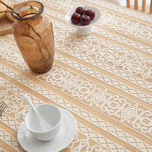 Close-up of off-white lace tablecloth with intricate geometric floral embroidery patterns