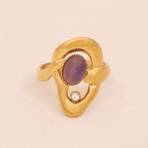 Detailed close-up of golden wavy ring featuring purple oval stone and white zircon