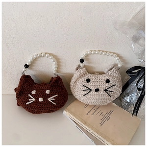 Detail of crochet cat-shaped handbags with large pearl handles and cute embroidery