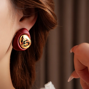 Close-up of model wearing gold-plated red enamel teardrop earrings with a vintage finish