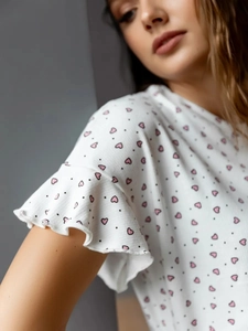 Vue détaillée du haut de pyjama blanc pour femme avec cœurs roses et manches volantées