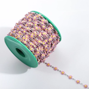 Close-up of pink and yellow enamel daisy chain on silver metal links wound on a spool