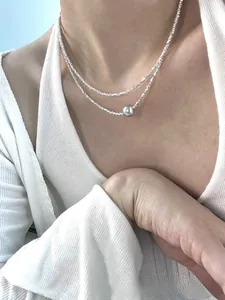 Detail of layered S925 silver necklace with crushed silver links and a grey pearl pendant
