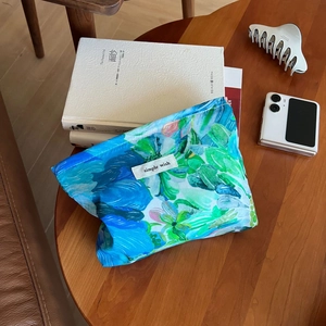 Detailed close-up of blue floral cotton makeup bag with Simple Wish label on wooden table