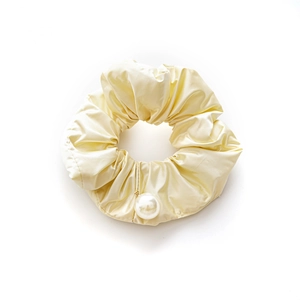 Elegant pale yellow satin scrunchie with hanging pearl charm on a clean white background