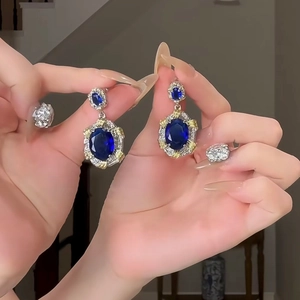 Close-up of elegant long tassel flower earrings featuring blue gems and diamond accents