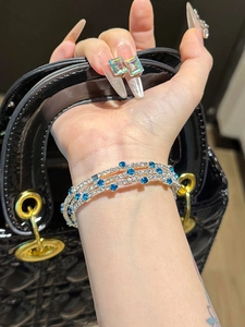 Detail of silver triple-layer bracelet with white zircons and blue gemstones on wrist