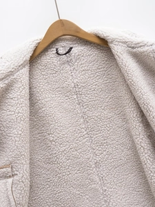 Close-up of curly sherpa fleece lining on a beige vest with a wooden hanger detail