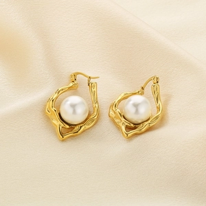 Irregular textured 18k gold earrings with large white pearl on beige silk background