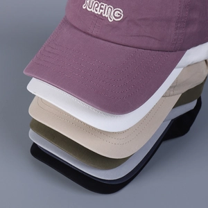 Detail of stacked cotton baseball caps in multiple colors with SURFING embroidery detail