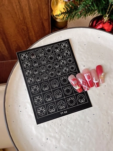 Detailed view of Christmas nail art stickers featuring white snowflakes and festive motifs