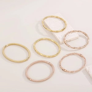 Macro detail of 18K gold plated bamboo link bracelets with polished metallic finish
