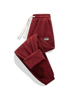 Dettaglio dei pantaloni sportivi bordeaux in pile con coulisse bianca e patch