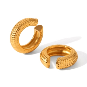 Macro detail of golden C-shaped ear cuff with scale texture and hollow stripe design