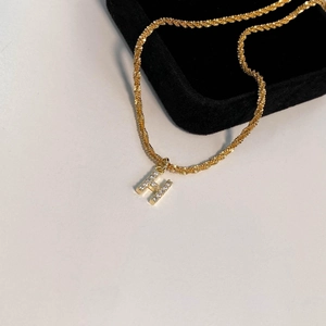 Vue détaillée du collier doré avec un pendentif lettre H serti de zircons scintillants