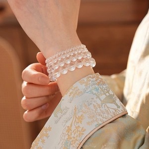 Detailed view of multi-layer clear white crystal bead bracelet worn with silk fabric