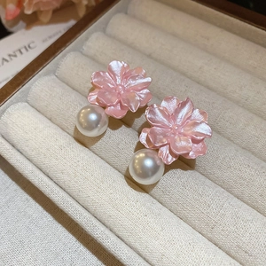 Macro shot of pink resin flower earring with white pearl drop on velvet display